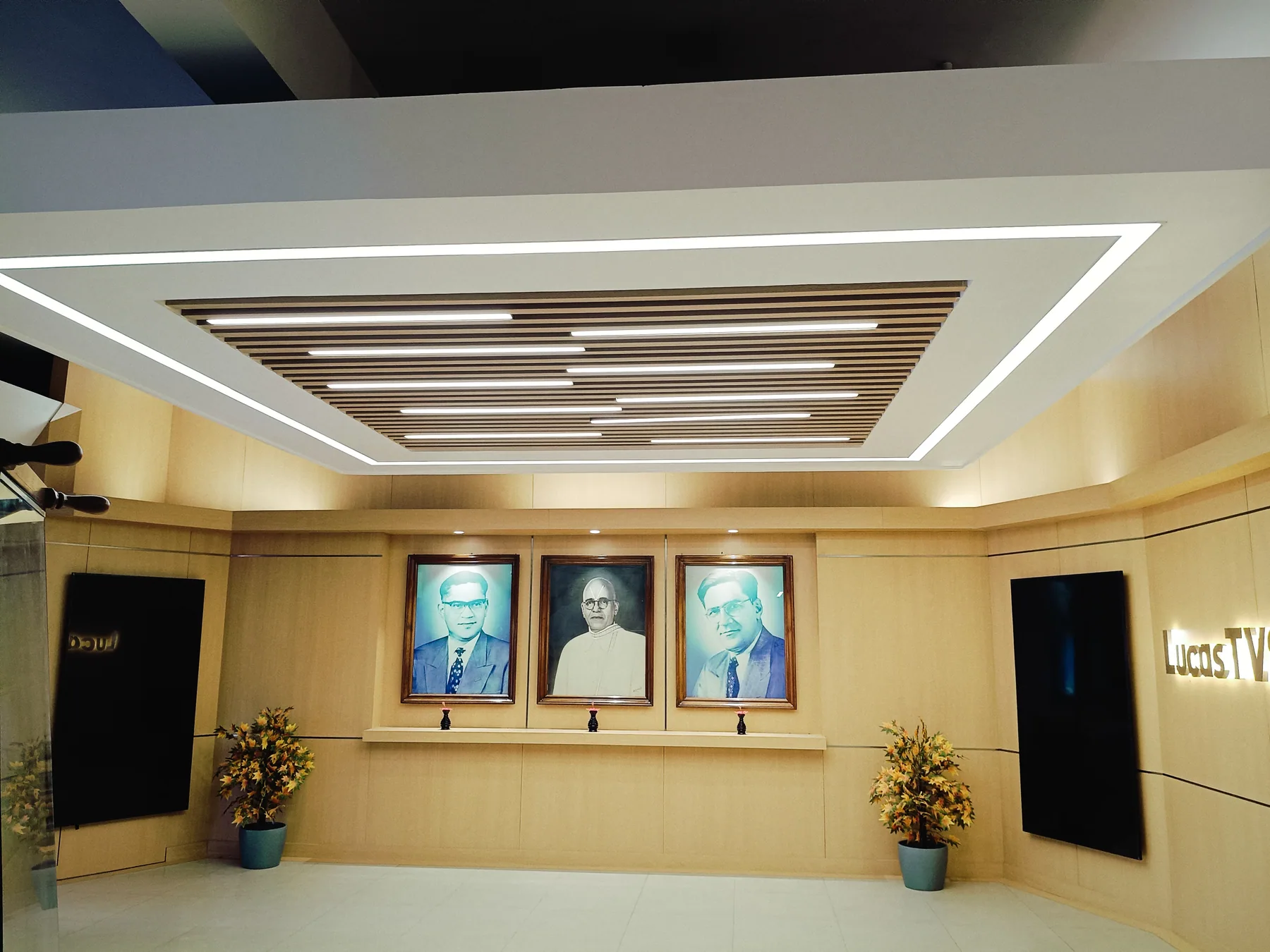 Slatted ceiling and linear lighting above the portrait wall